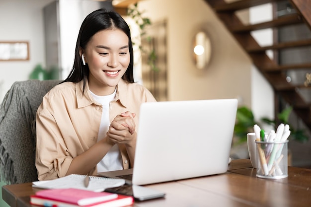 Aziatisch meisje studeert thuis met behulp van laptopcomputer jonge vrouw volgt online lessen webinar of video...