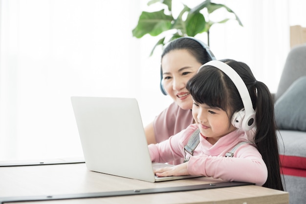 Foto aziatisch meisje studeren met laptop en headset, schriftelijke cursus met sociale afstand nemen