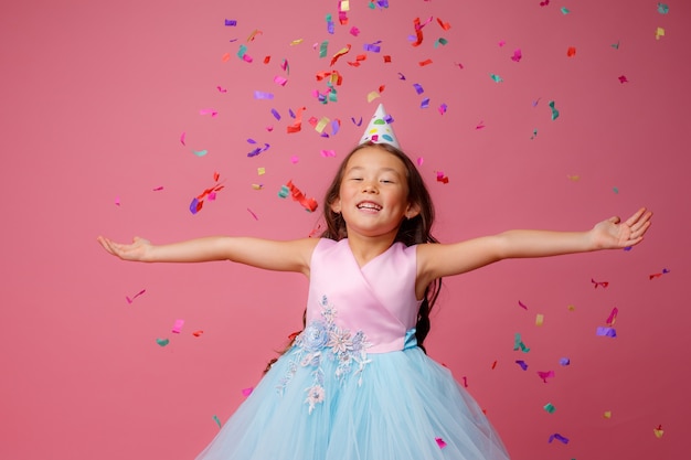 Aziatisch meisje viert verjaardag klappen vangt confetti op roze