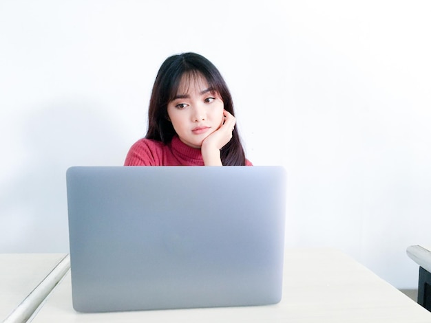 Aziatisch mooi haarmeisje is verward of verveeld aan de voorkant van de laptop op de geïsoleerde witte achtergrond