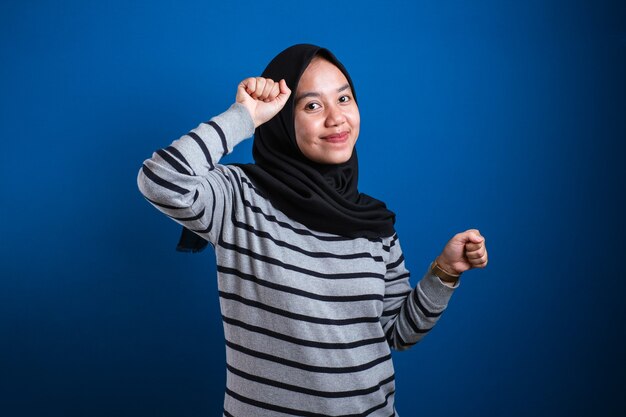 Aziatisch moslimmeisje die hijab draagt die gelukkig vreugdevol danst en viert de overwinning van het goede nieuws