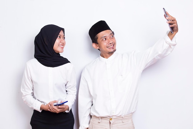 Aziatisch moslimpaar die slimme telefoon gebruiken die op witte achtergrond wordt geïsoleerd