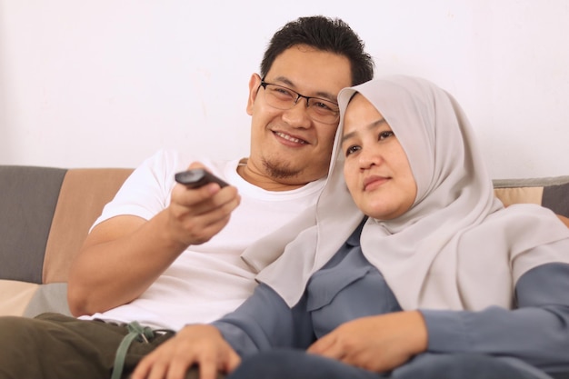 Aziatisch moslimpaar knuffelt tv kijken op de bank man en vrouw quality time doorbrengen