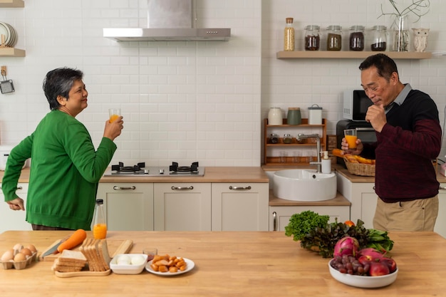 Aziatisch oudere volwassen koppel koken gezond eten samen thuis terwijl ze dansen in de keuken ochtend weekendgeluk Aziatisch oud getrouwd koppel genieten van romantische geknipte opname van een oudere koppel dansen