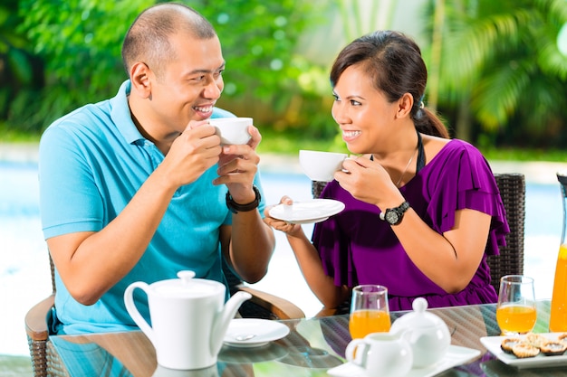 Aziatisch paar dat koffie op huisportiek heeft