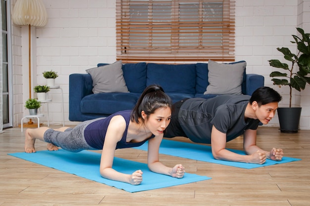 Foto aziatisch paar dat samen thuis in de woonkamer traint sportconceptoefening voor een goede gezondheid