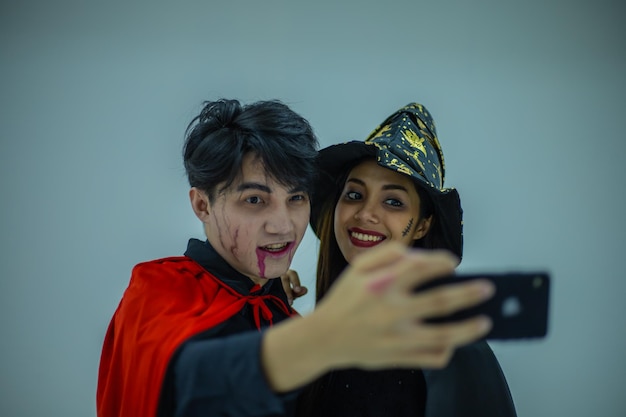 Aziatisch paar die heksenkostuum dragen die selfiefoto op mobiele telefoon nemen