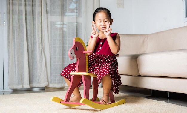 Aziatisch schattig klein meisje swingend speelgoedpaard