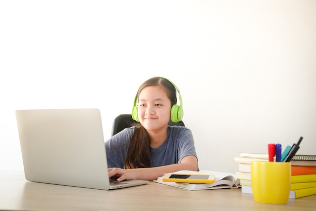 Aziatisch schoolmeisje Leer online vanuit huis via videogesprekken. Een laptop gebruiken om met docenten te communiceren. Concept van online onderwijs. Social distancing om de verspreiding van het coronavirus te verminderen.
