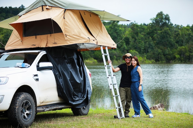 Aziatisch stel ontspannen met een camper op het dak in de buurt van de rivier