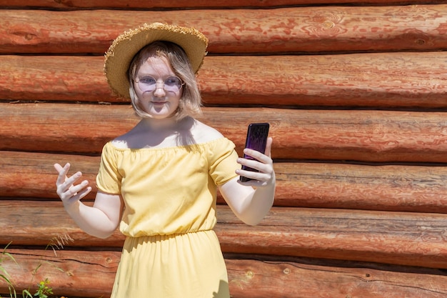 Aziatisch tienermeisje met hoed en zonnebril heeft online videogesprekchats tegen een houten muur