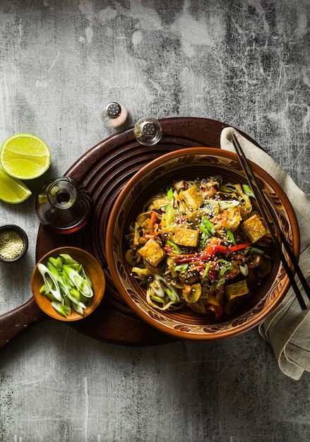 Aziatisch veganistisch roerbakgerecht met tofu, rijstnoedels en groenten, bovenaanzicht.