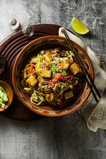 Aziatisch veganistisch roerbakgerecht met tofu, rijstnoedels en groenten, bovenaanzicht.