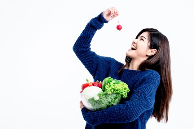 Aziatische aantrekkelijke vrouwenholding en glimlach gelukkig met het eten van verse groenten en fruit