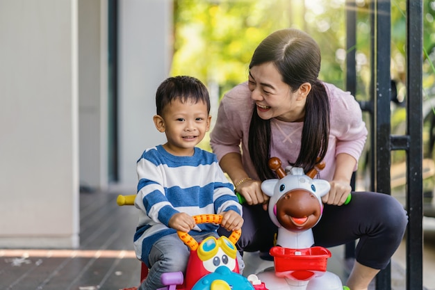 Aziatische alleenstaande moeder met zoon speelt samen met auto speelgoed bij het wonen in een modern huis