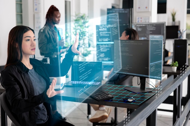 Aziatische app-ontwikkelaar die met hologram werkt en probeert een beveiligingssysteem te creëren in het big data-kantoor. Gebruik van holografisch beeld en nieuwe interface voor cloud computing, programmeren van databasecodes.