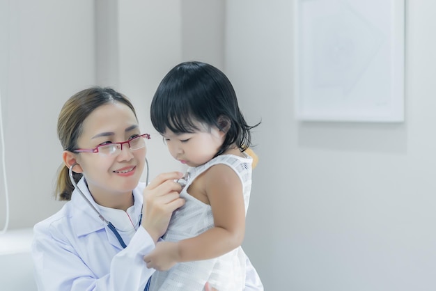 Aziatische arts die een stethoscoop gebruikt om zijn ademhaling te controleren en het hart van een lief meisje controleert de gezondheid van kinderen in Thailand