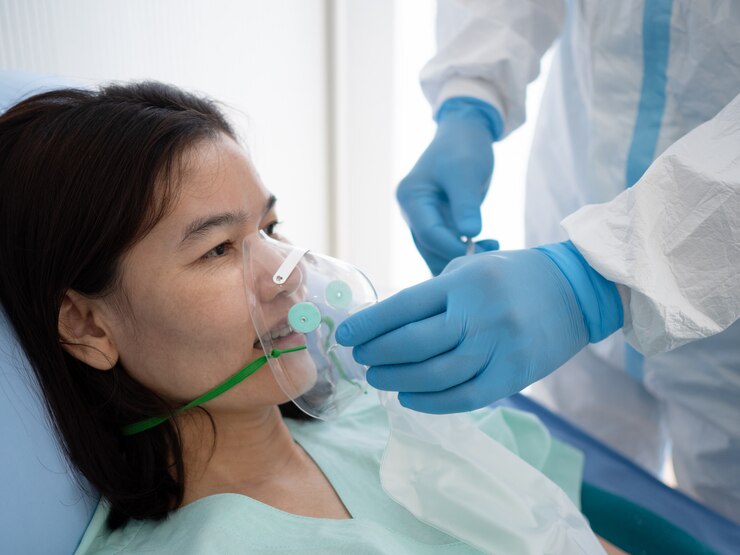Aziatische arts draagt PPE-pakbehandeling en gebruikt zuurstofmasker of noodinhalatiemasker met coronavirus-geïnfecteerde patiënt in quarantainekamer met negatieve druk. Medisch en gezondheidsconcept.