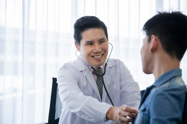 Aziatische arts gebruikt een stethoscoop om de patiënt met een handicap te controleren