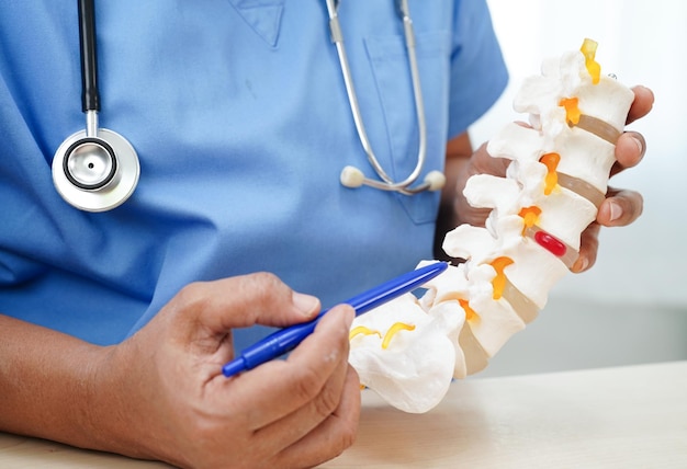 Aziatische arts met ruggenmergzenuw en botmodel Lumbale ruggengraat verplaatst hernia-schijffragment