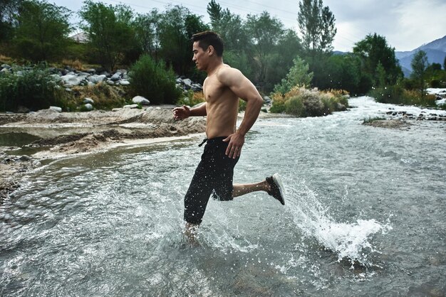 Aziatische atleet op een ochtendrun op de rivier, Kazachse jogger in de natuur close-up