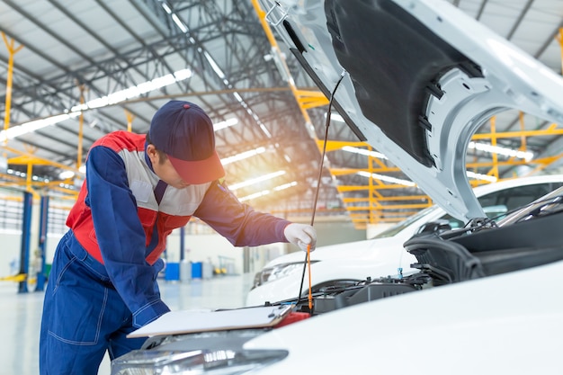 Aziatische auto-monteur gedetailleerde voertuiginspectie.