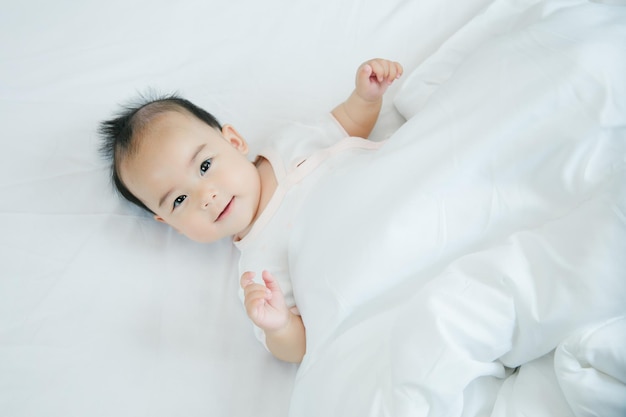 Aziatische baby liggend op bed met zachte deken binnenshuis schattige kleine Aziatische pasgeboren baby