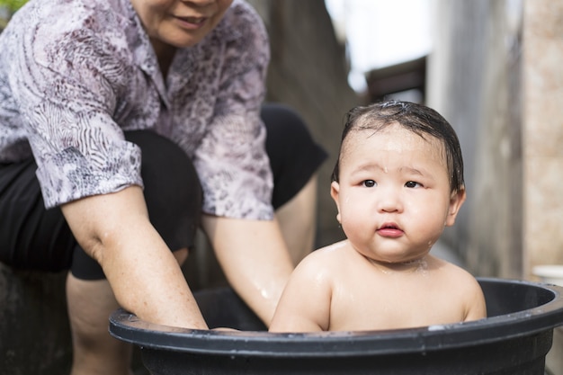 Aziatische baby neemt buiten een bad.