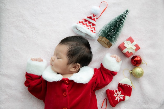 Aziatische baby pasgeboren op de eenvormige slaap van de Kerstman met rode doos huidige en rode hoed