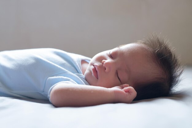 Aziatische baby slaapt op grijs bed