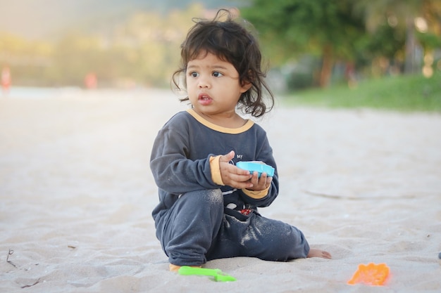 Aziatische babymeisje strand speelgoed spelen op het zandstrand in de buurt van de zee