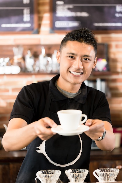 Aziatische Barista biedt een kop koffie met dripbrouw