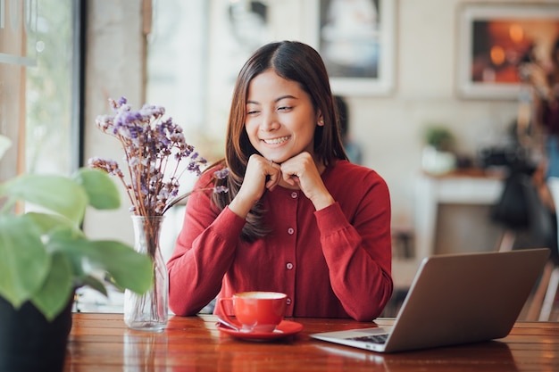 Aziatische bedrijfsmeisje werkende en het drinken koffie in koffie met laptop