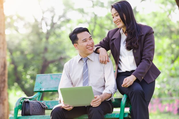 Aziatische bedrijfspaarmannen en vrouwen het werkontspanning in park met laptop