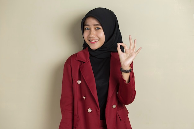 Aziatische bedrijfsvrouw die hijab met omhoog hand beduimelt ok draagt