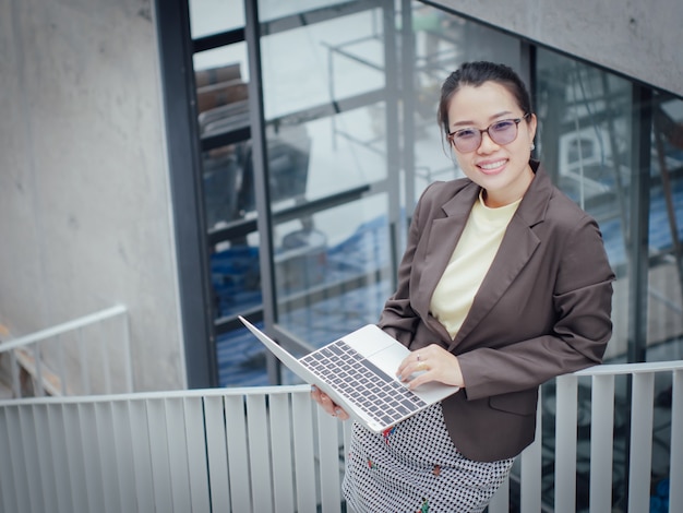 Aziatische bedrijfsvrouw met gelukkig laptop en het werk van het glimlachconceptensucces