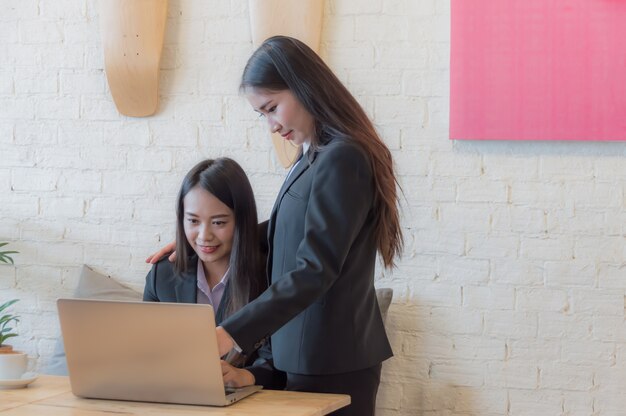 Aziatische bedrijfsvrouwen die notitieboekje voor ontwerper gebruiken op het werk.