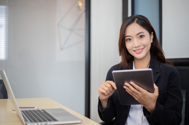 Aziatische bedrijfsvrouwen die tablet voor het werken op kantoor gebruiken ontspannen tijd en het glimlachen