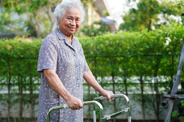 Aziatische bejaarde gehandicaptenpatiënt loopt met rollator in medisch concept voor verpleegziekenhuizen