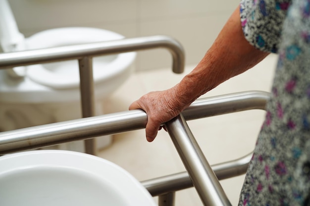 Aziatische bejaarde oude vrouw patiënt gebruik toilet steunrail in badkamer leuning veiligheid handgreep beveiliging in verpleegziekenhuis