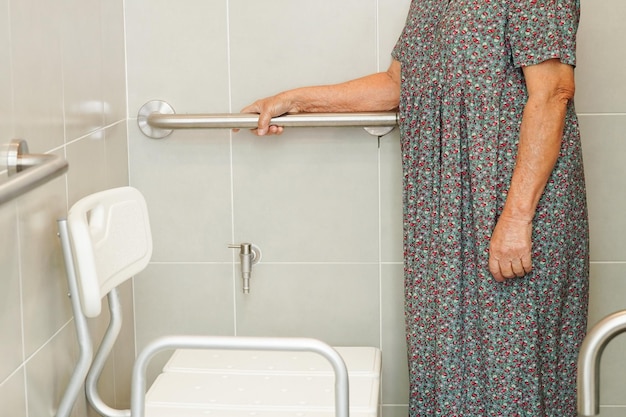 Aziatische bejaarde oude vrouw patiënt gebruik toilet steunrail in badkamer leuning veiligheid handgreep beveiliging in verpleegziekenhuis