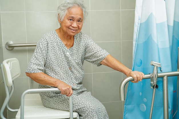 Aziatische bejaarde oude vrouw patiënt gebruik toilet steunrail in badkamer leuning veiligheid handgreep beveiliging in verpleegziekenhuis
