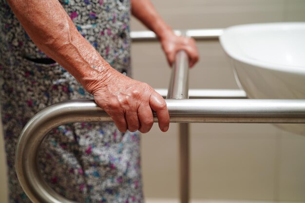 Aziatische bejaarde oude vrouw patiënt gebruik toilet steunrail in badkamer leuning veiligheidsgreep