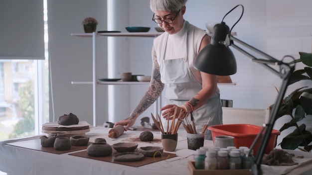 Aziatische bejaarde vrouw geniet van aardewerk thuis Een vrouwelijke keramist maakt nieuw aardewerk in een studio