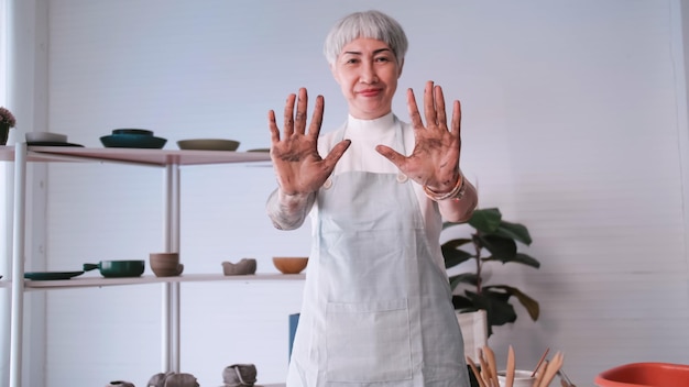 Foto aziatische bejaarde vrouw geniet van aardewerk thuis een vrouwelijke keramist maakt nieuw aardewerk in een studio