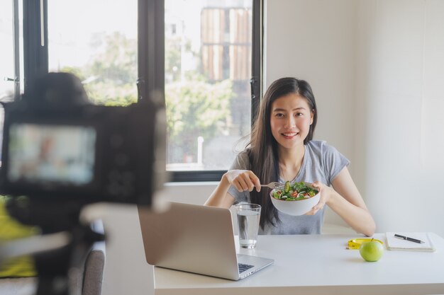 Foto aziatische blogger die salade eet en video opneemt