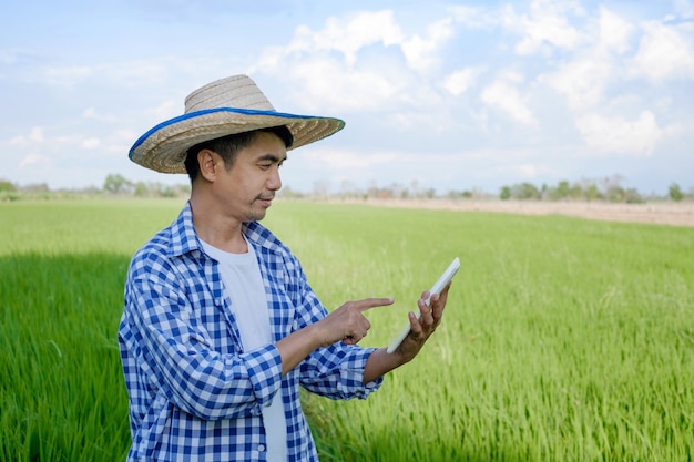Aziatische boer man met smartphone tabletcomputer op groene boerderij