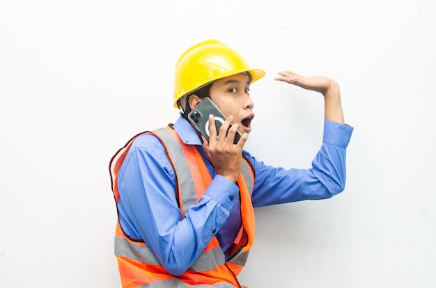 aziatische bouwvakker die een telefoon vasthoudt met geschokte, verraste en verbaasde uitdrukkingen.