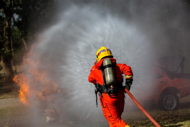 Aziatische brandweerman dienstdoende brandbestrijding Aziatische brandweerman spuit water onder hoge druk Brandweerman in brandblusapparatuur uniform spuitwater uit slang voor brandbestrijding