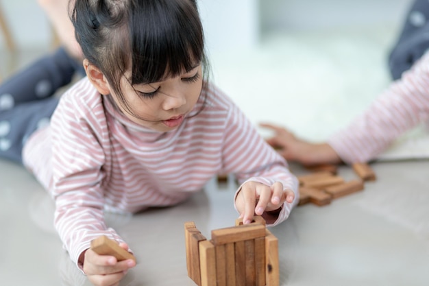 Aziatische broer of zus die thuis houten stapels speelt